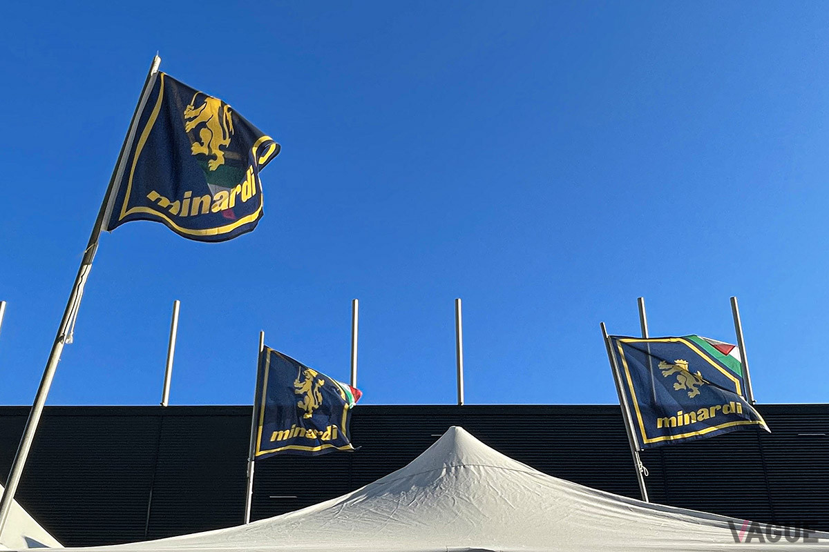 青空のもと、風になびくミナルディの旗