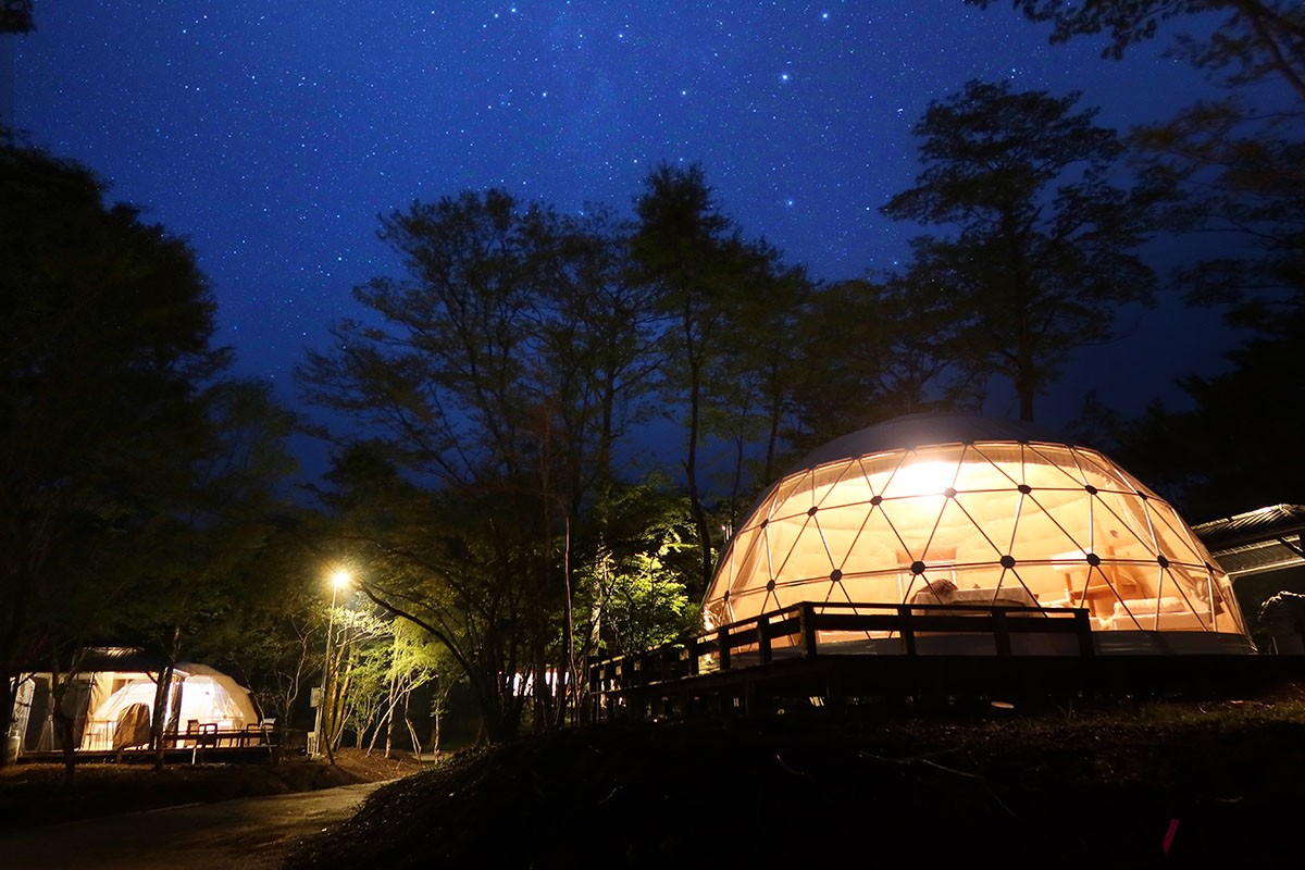 標高1000mを超す十里木高原に誕生した「MOSS十里木キャンプリゾート」は、ドーム型グランピングテントやトレーラーハウスを配した広大な敷地に建つ