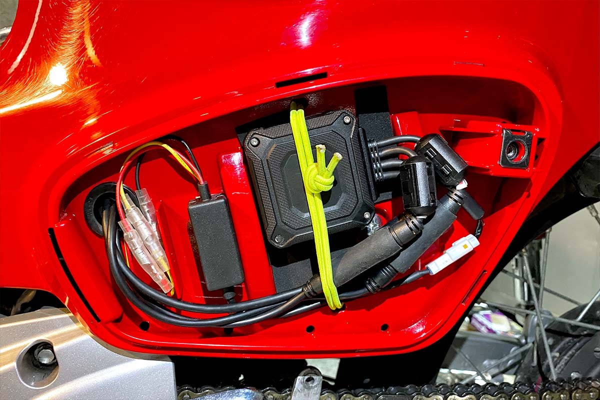 コンパクトな金属ケースの本体とシンプルな配線で、車体の隙間に設置することが可能。スーパーカブならサイドカバー内に無理なく収まります