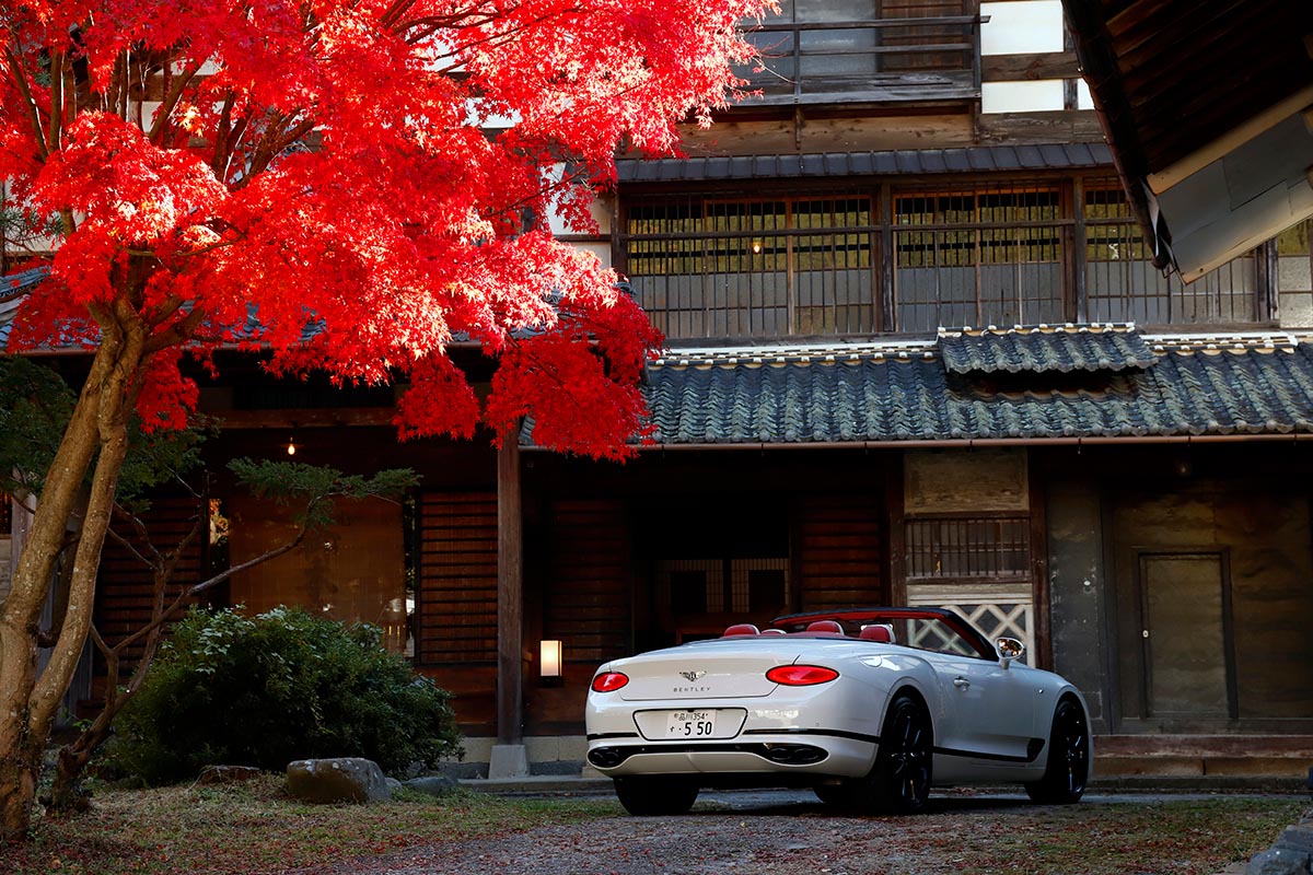 歴史を感じさせる建物と真っ赤な紅葉。真っ白なコンチネンタルGTCとのコントラストがまぶしい