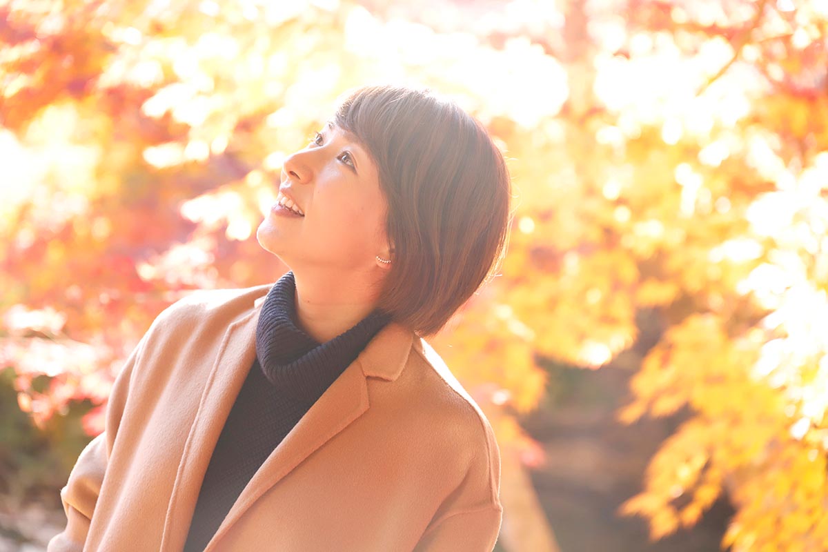 都心ではまだ目にすることのできない真っ赤な紅葉に、思わず微笑む彼女