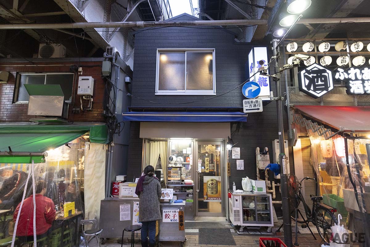 白地に紺の文字の看板が目印。頭上は山手線・京浜東北線の高架が