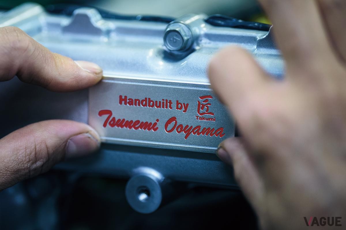 赤文字で匠の名が刻まれたアルミ製ネームプレートと、ゴールドのモデルナンバープレートを、新たにエンジンルーム内に採用