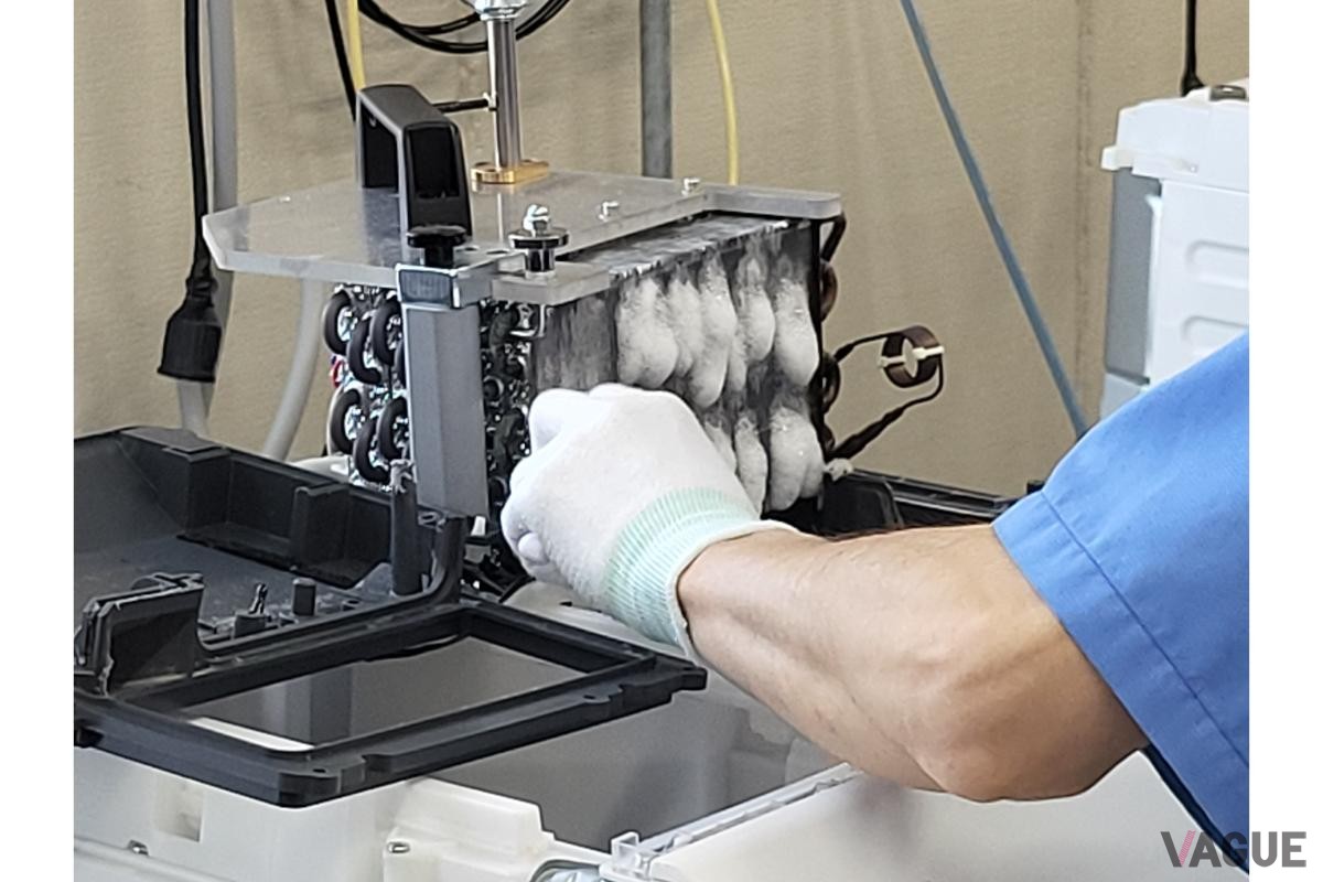 熱交換器を慎重にブラシで清掃する技術者。細かな手作業が家電に再び生命を吹き込む。