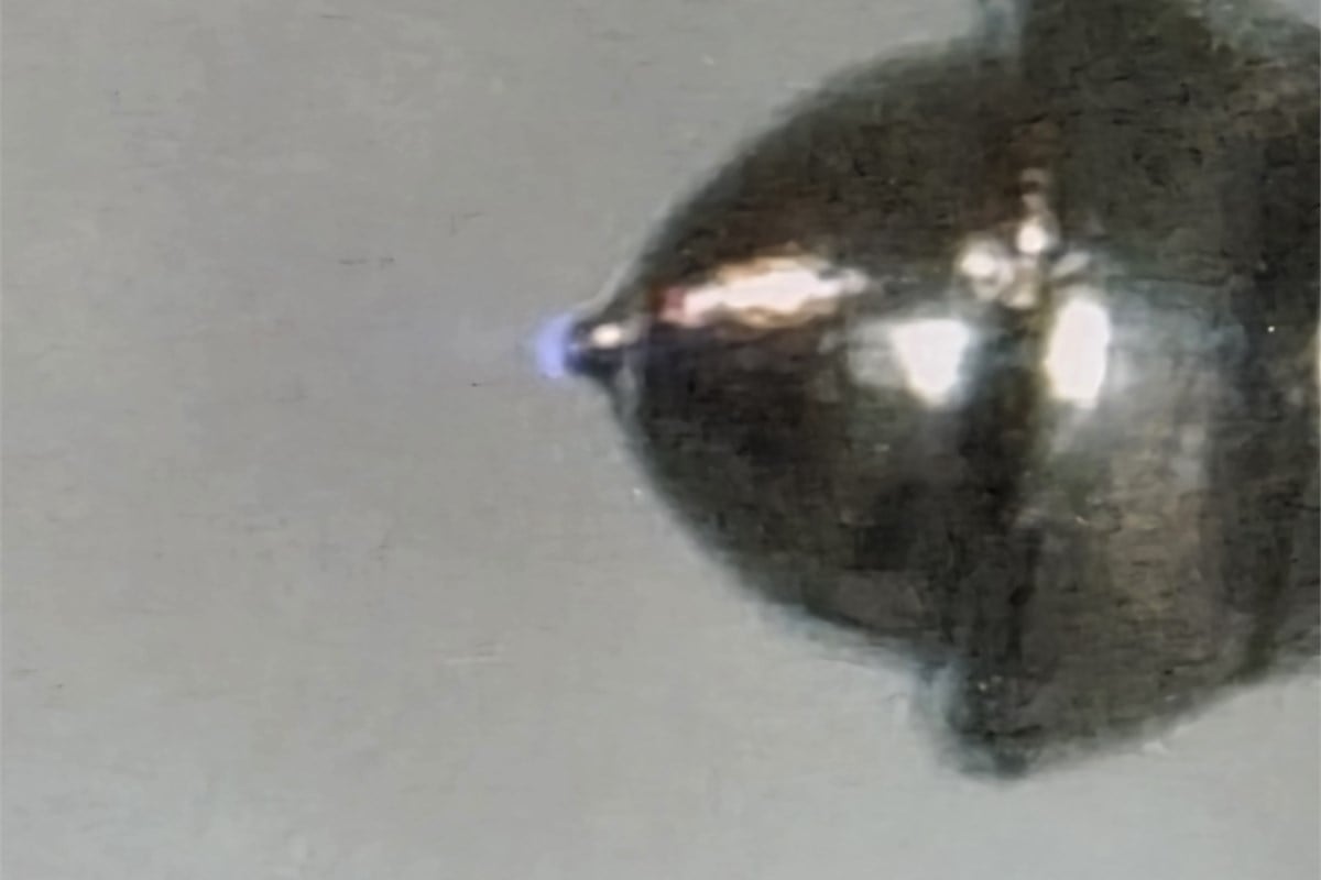実演装置のモニターに映し出された、ナノイー発生部の拡大映像。電極付近に青白い光が見えます。これは発生の仕組みを理解するための観察で、ナノイーの粒子そのものや、髪の中へ入る様子を写した写真ではありません。