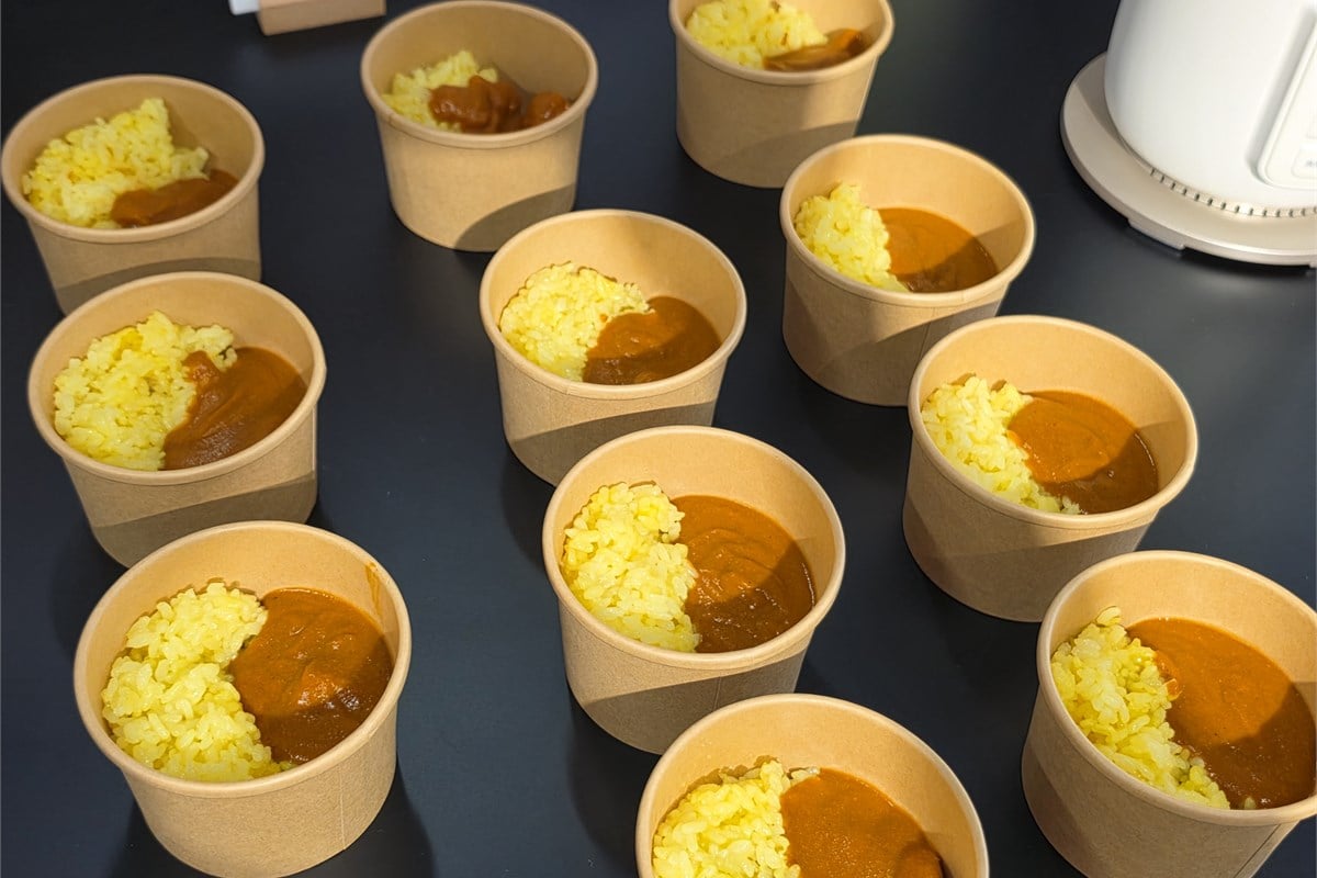会場の試食コーナーに並んだバターチキンカレー。従来のポタージュやスムージーに加え、主食につながる料理も提案する。具材感を残す場合には工程途中で材料を取り出すなど、料理に応じた工夫が必要になる。