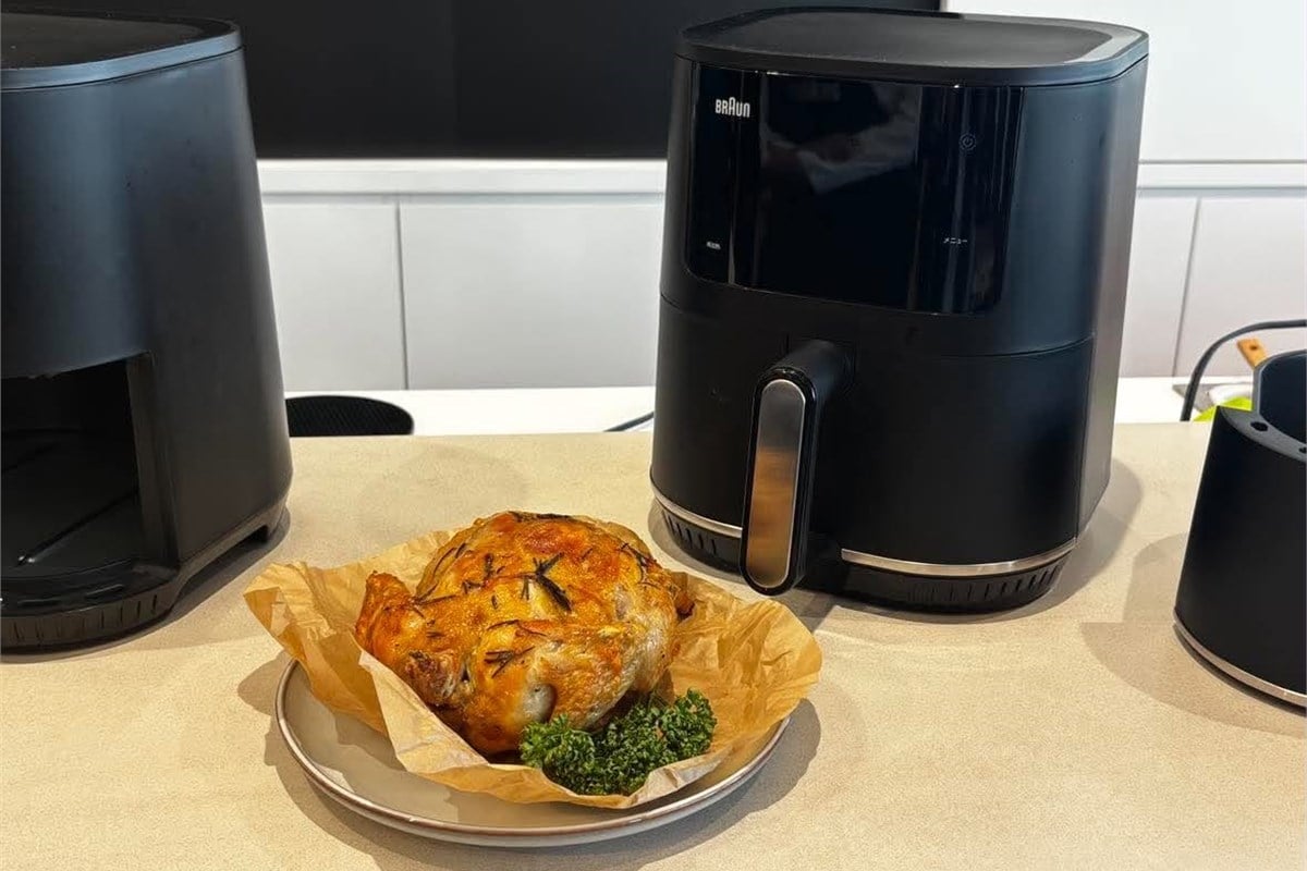 ブラックの本体と、会場に並んだ焼き上がりの鶏料理。マルチフライ3は唐揚げ風の調理だけでなく、肉や魚、野菜のグリルなどにも対応する。キッチンで日常的に使うためには、メニューの幅と本体の設置スペースの両方が判断材料になりそうだ。