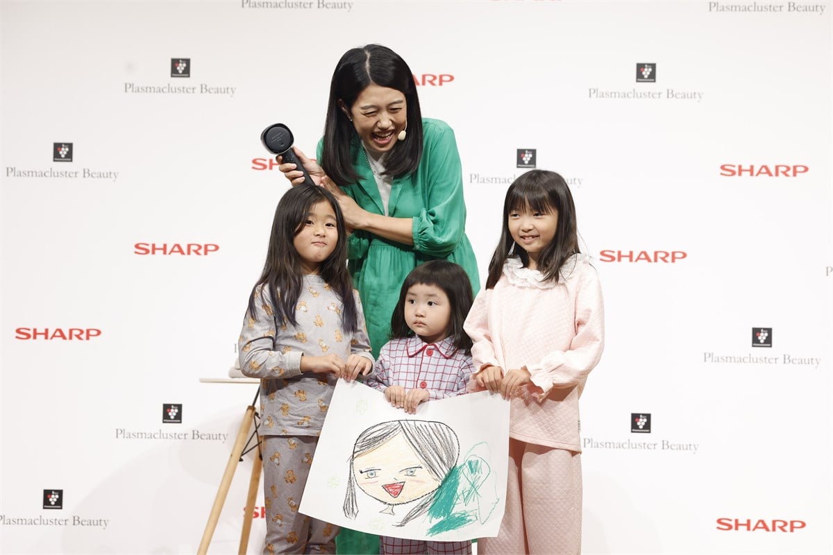 3人の子役と横澤さんによるフォトセッション。子どもたちが描いた似顔絵とともに、実演で使用したドライヤーも披露しました。子育て中は家族全員のヘアドライが毎日の作業になりますが、時短だけでなく熱さや使いやすさにも配慮した製品設計の意味が見えてきます。