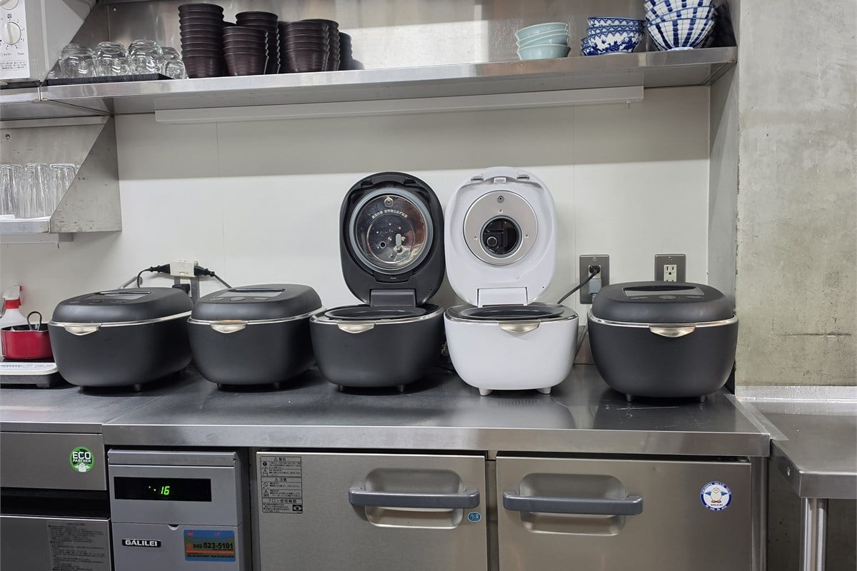 「なるたけ」の厨房に並ぶ炊飯器。高級炊飯器の価値を量販店の売り場だけで説明するのではなく、飲食店で実際に食べてもらうことで「おいしい」から技術へ関心をつなげる試みだ。