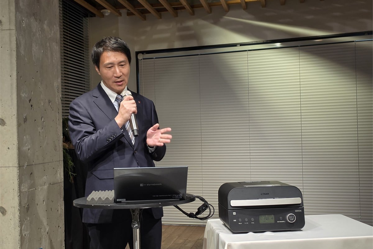 新製品の戦略を説明するタイガー魔法瓶の調理ブランドマネージャー、福富博史氏。従来の自動調理鍋は煮込み中心で日常の主菜に使いにくいなどの課題があり、使用頻度の高い「焼く」を自動化する狙いを語った。