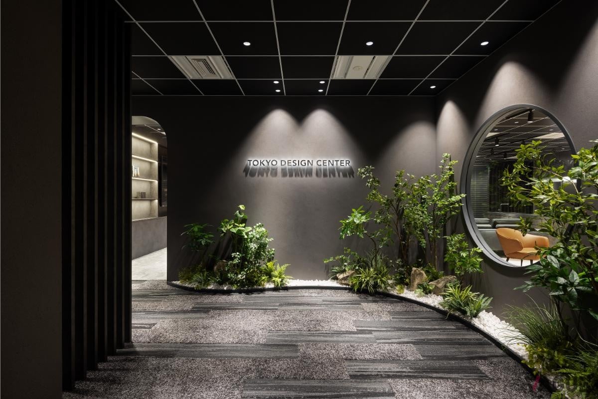 Tokyo Design Centerのエントランスはグリーンの植物が配置され、中央にはロゴがモダンに輝く