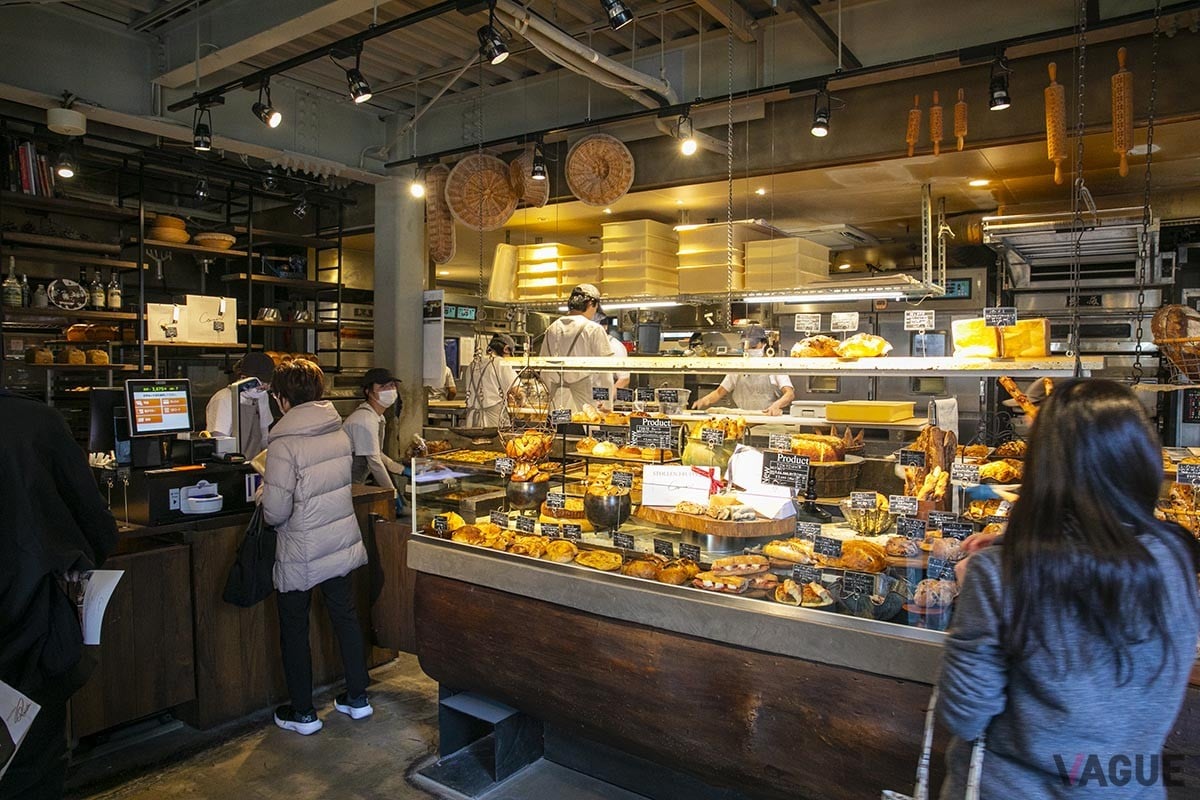 天井の高い店内には約60種のパンが並ぶ。のし棒やカゴなどがぶら下がりおしゃれな雰囲気