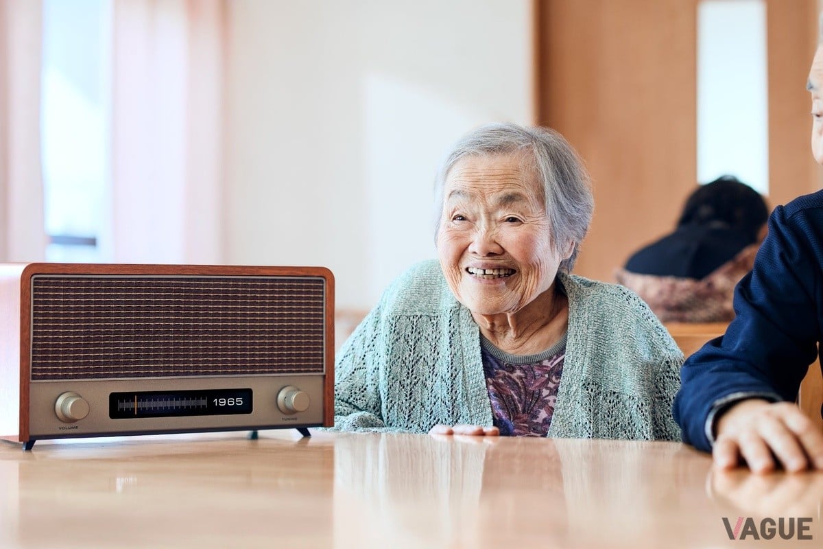 ニチイ学館の介護施設で実施された実証実験の様子。懐かしいニュースや音楽が流れることで利用者同士やスタッフとの会話が自然に生まれ、高齢者の表情が変わる。施設内のコミュニケーションが活性化したという。笑顔が平均8.7%増加、発話量も10%以上増えることが確認された