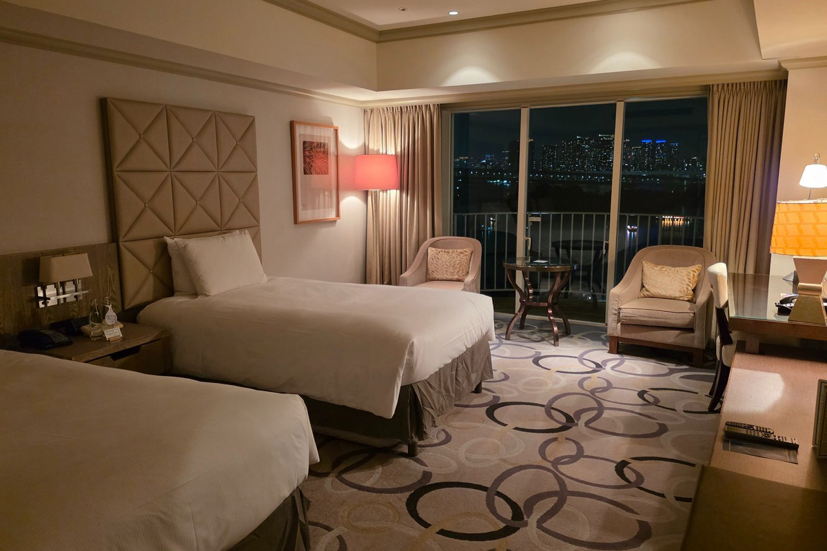 「Private Night Retreat」プランで確約されるバルコニー付きのベイビュー客室。ゆったりとしたくつろぎのプライベート空間から、東京湾のきらめく夜景を独占できる