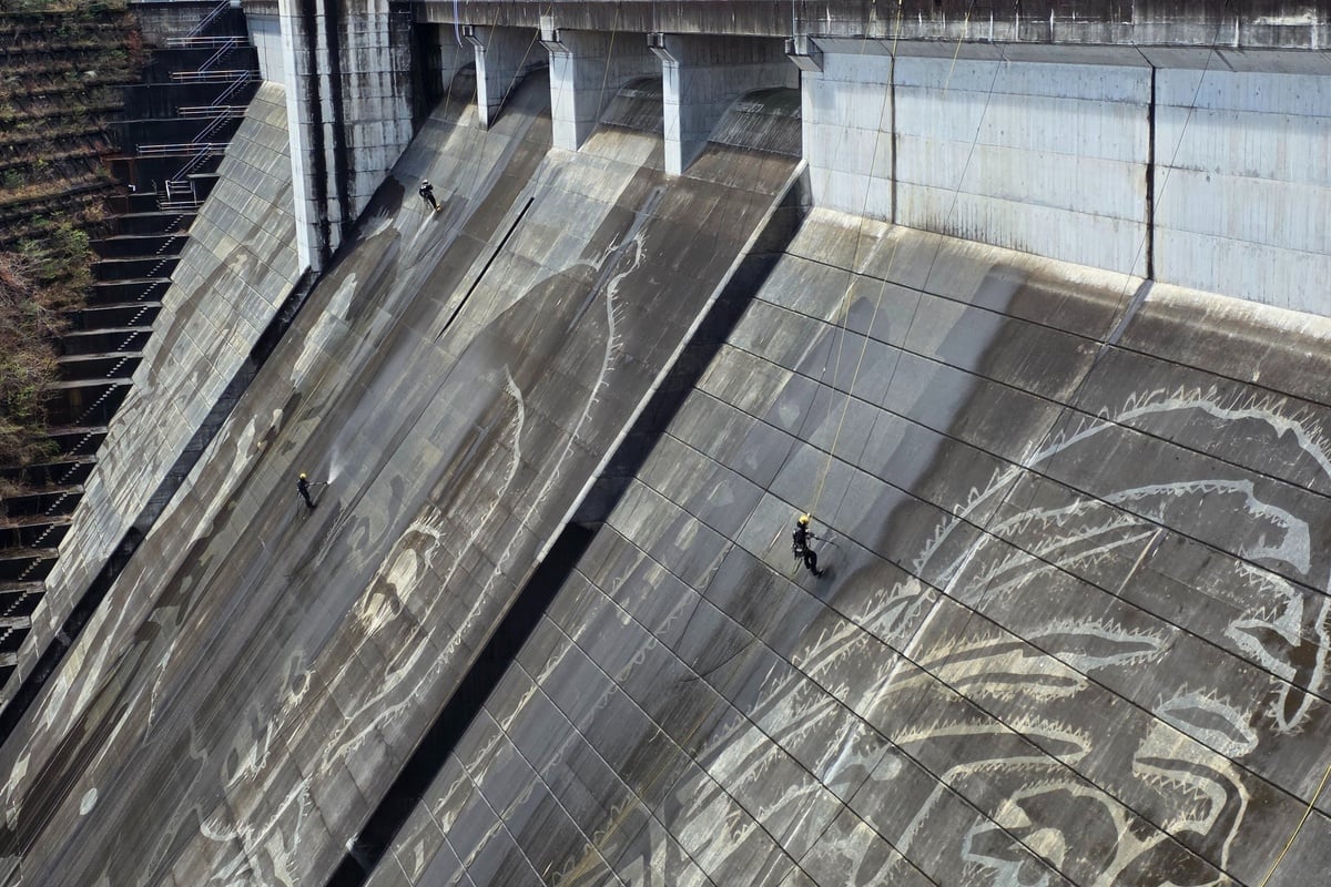 松田川ダムは堤高56.0m、堤頂長228.0m、堤体積166.4千立方メートルを誇る重力式コンクリートダム。堤体に降りていくケルヒャーのチームメンバーたち。水圧で表面の汚れを削ぎ落とし、侍の輪郭を少しずつ立ち上げていく工程。何かを“描く”というより、そこに埋もれていた像を“現す”感覚こそ、リバース・グラフィティの本質をよく物語っている