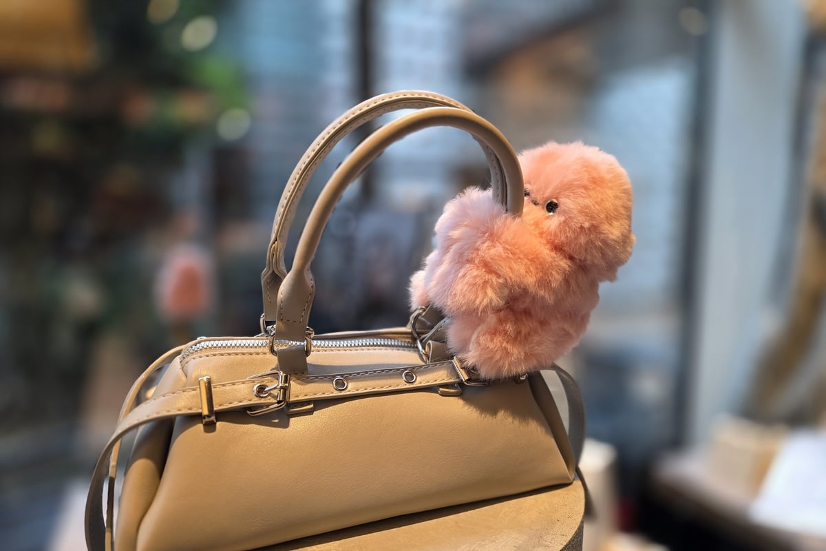 バッグの持ち手に抱きつくように取り付けられたピンクのmirumi。チャームロボットとして持ち歩く時のサイズ感と装着イメージがわかる