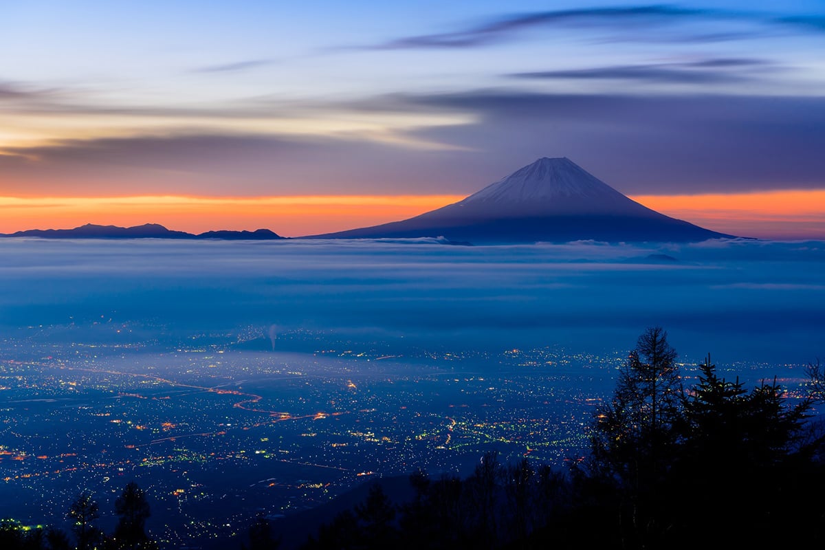 雲海とともに浮かび上がる富士山と街の灯りが、非日常のひとときを演出