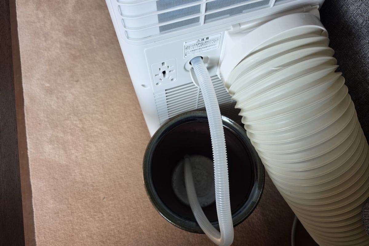 除湿モードや冷風モードを高湿度の環境で長時間運転する際は、付属のドレンホースを背面へ接続して連続排水が可能。今回は本体の下へ容器を置き、室内から取り除いた水分を受けるようにした