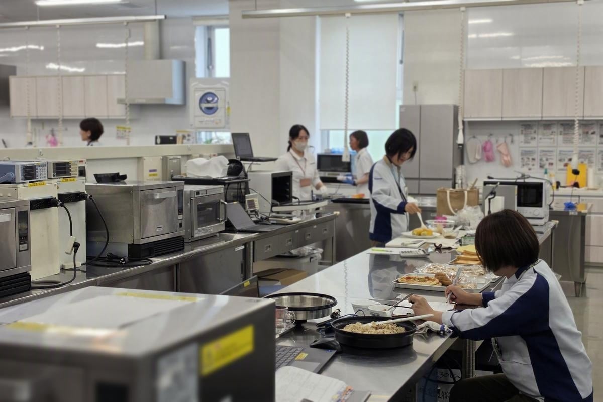 Panasonic Cooking @Labの調理家電開発現場。電子レンジや調理機器が並ぶラボで、担当者たちが実際の食材を前に検証を重ねている。ボタンひとつの便利さの奥にある仕事を象徴する一枚