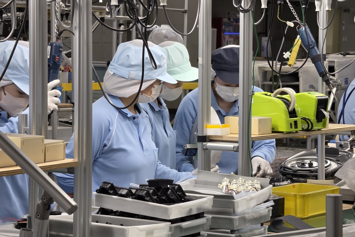 蓋まわりの部品を組み込む作業。作業者同士が近い距離で工程を分担し、必要に応じて熟練者が指導しながら技術を継承し、複雑なユニットを形にしていく