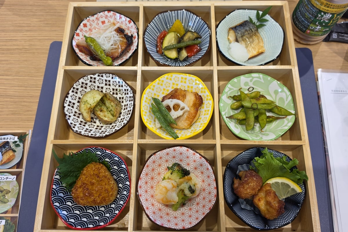 焼きサバ、彩り野菜の焼き浸し、豚ロースのみそ焼き、枝豆ペペロンチーノ、照り焼きチキン、のり塩ポテト、唐揚げ、冷凍エビとブロッコリー、焼きおにぎりを盛り込んだ「おかず九品御膳」。日本の夕食を意識した構成だ