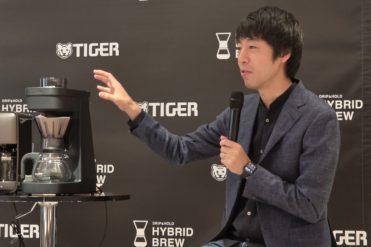 HYBRID BREWの実機を横に話す粕谷氏。従来モデルの開発には関与していないが、自身のYouTubeでタイガー独自の「透過×浸漬」という考え方に注目したことが、今回の発表会でゲストに招かれるきっかけになった。