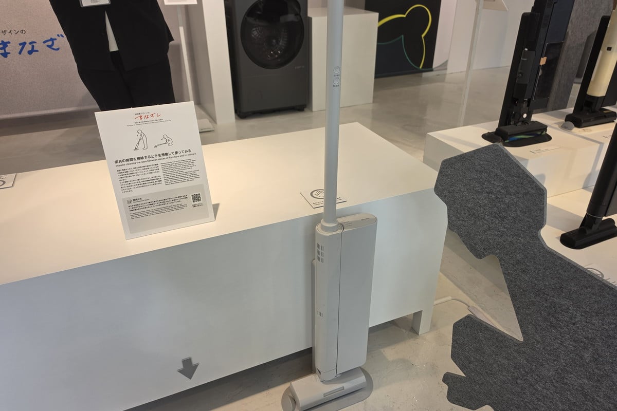 コードレス掃除機を家具の隙間へ差し込む場面を再現した展示。掃除機を正面から眺めるのではなく、生活動線や収納時の横姿まで想像することで、壁際にすっと収まる薄さや取り回しを考えている。