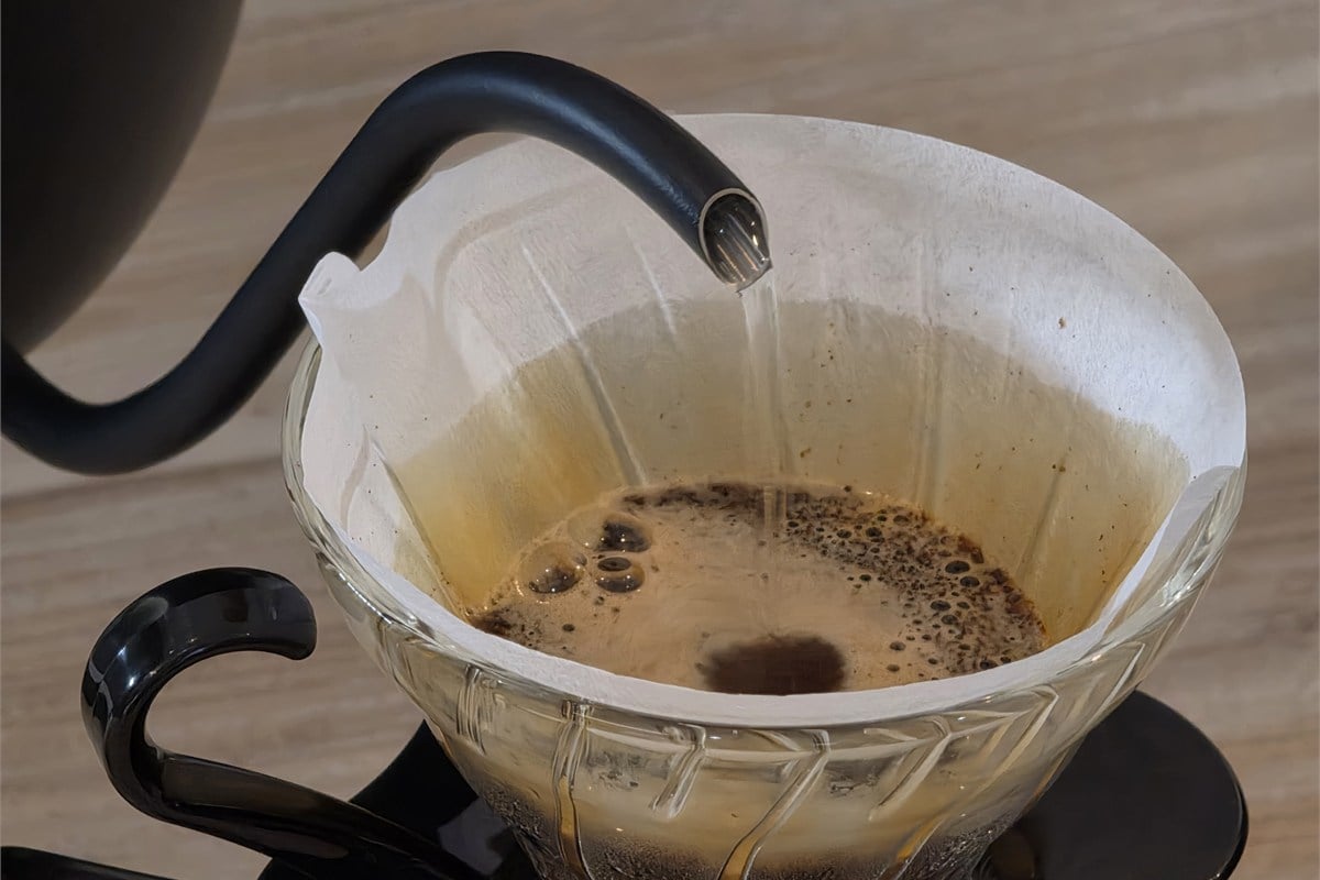 細い湯の流れをコーヒー粉へ落とすハンドドリップの実演。注ぐ位置と量を調整しやすいことは、抽出の再現性を考えるうえで大切な要素となる。味を一律に決めるのではなく、好みの一杯を探るための道具だ。